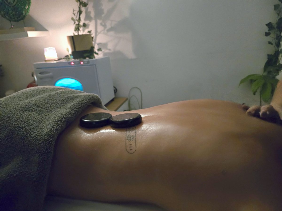 Dos piedras calientes apoyadas en la zona lumbar durante un masaje en NAGI