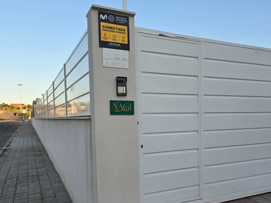 El portón blanco del número 22 de Calle Botánica con el rótulo verde y dorado de Nagi junto al telefonillo